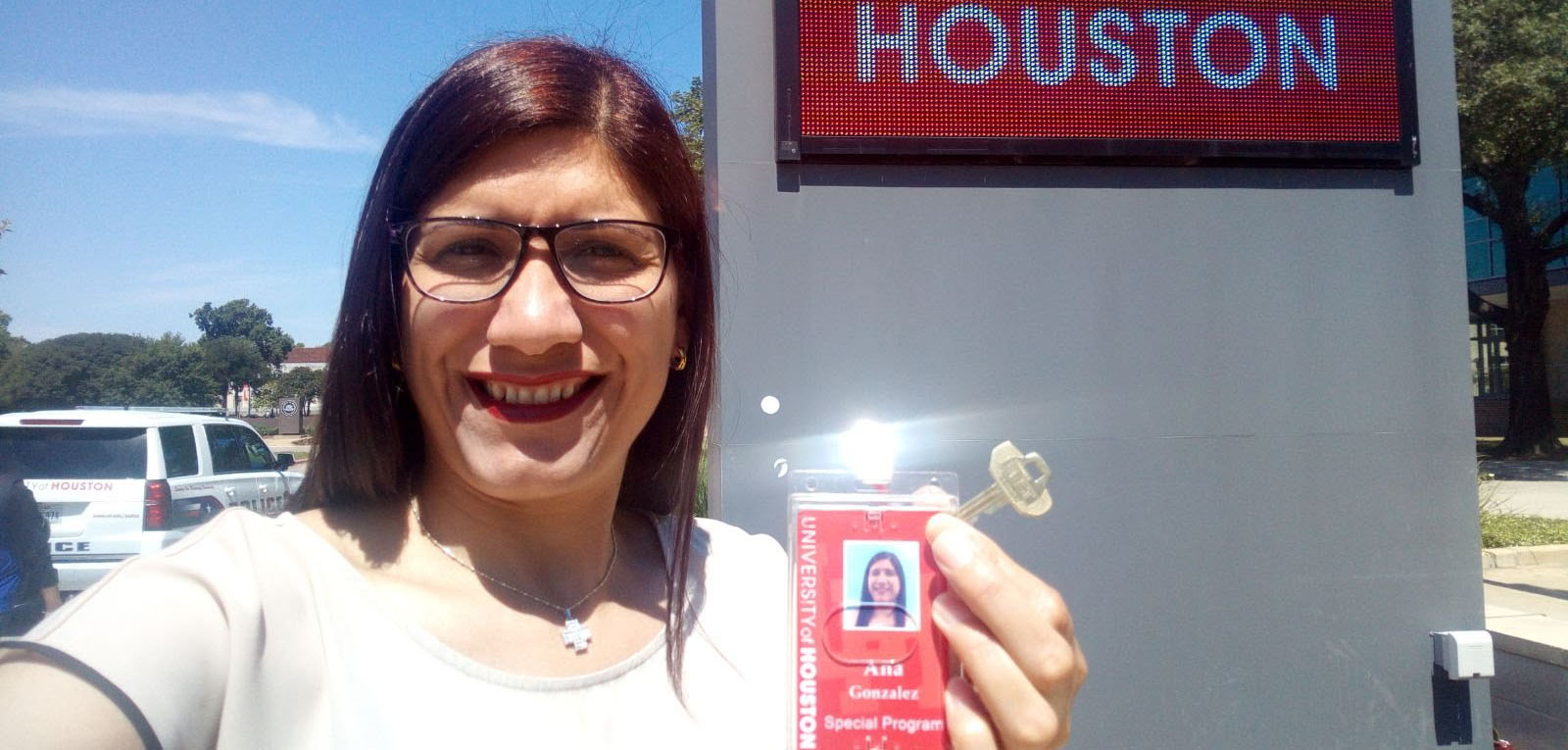 Ana Gonzalez holding her ID card in front of University of Houston sign