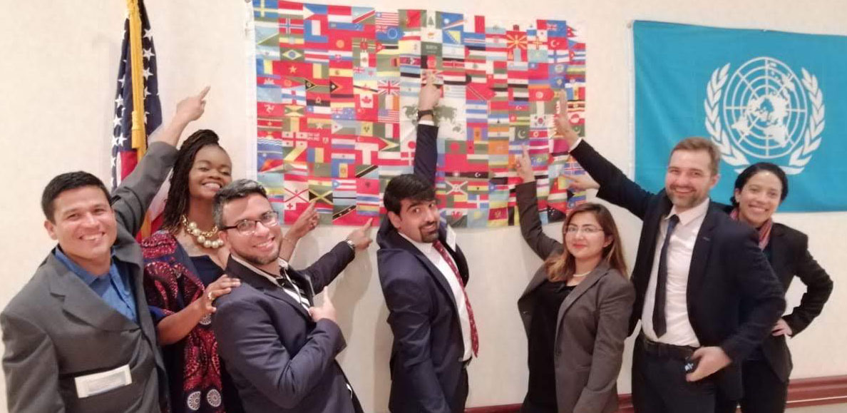 Fellows pointing to their country's flag on a flags of the world poster.